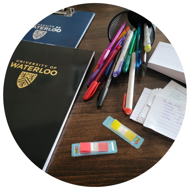 Pens and UWaterloo notebooks displayed on a desk