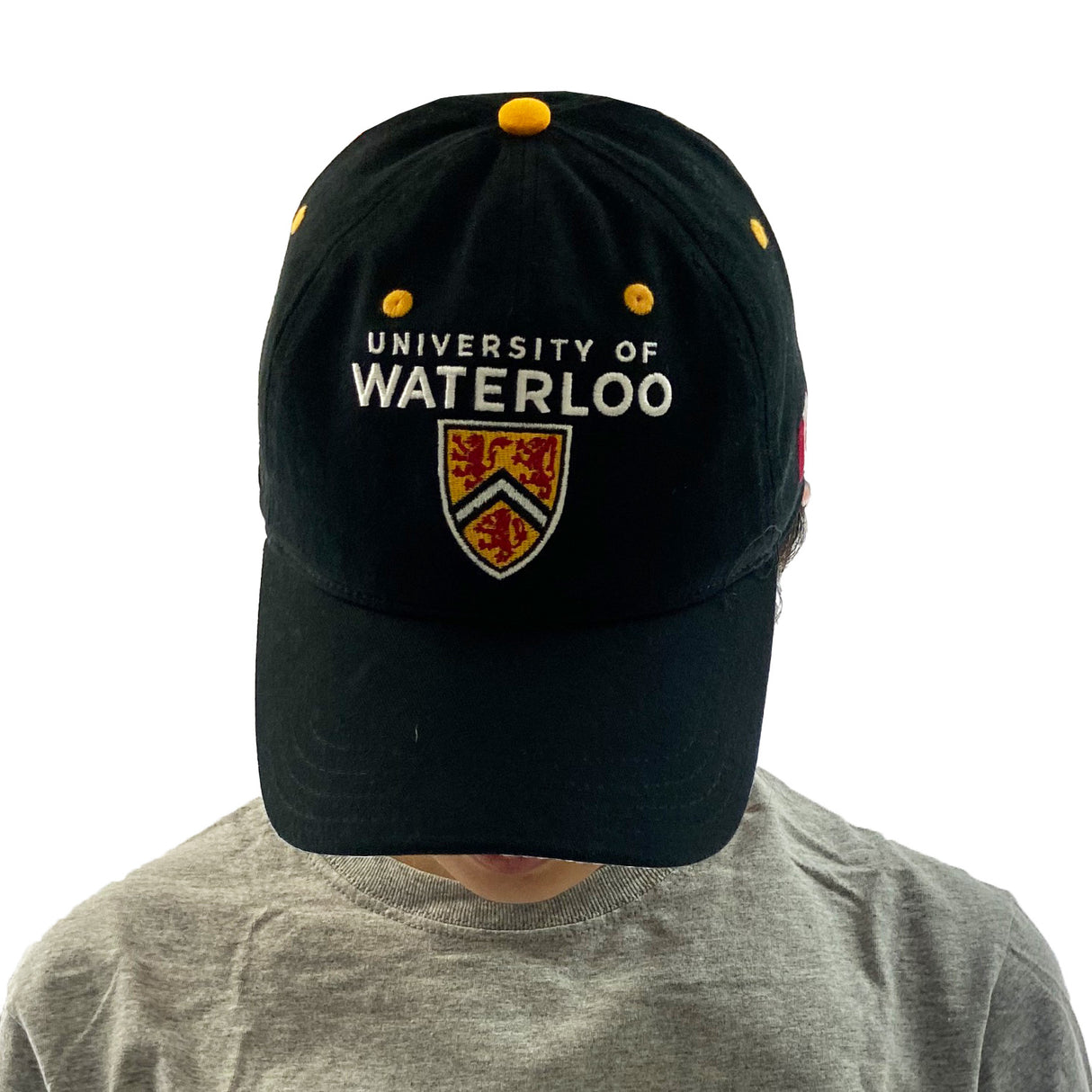 A person wearing a black University of Waterloo cap with a gray t-shirt, looking down.