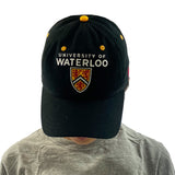 A person wearing a black University of Waterloo cap with a gray t-shirt, looking down.