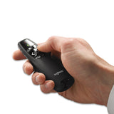 A hand holds a black Logitech remote control. The remote features buttons, including a directional arrow and a green light indicator on the top.