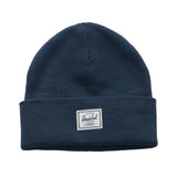 A navy blue beanie hat with a folded cuff and a white tag that reads "Herschel" on it.