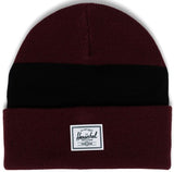 A maroon beanie with a black horizontal stripe and a white Herschel label on the front.
