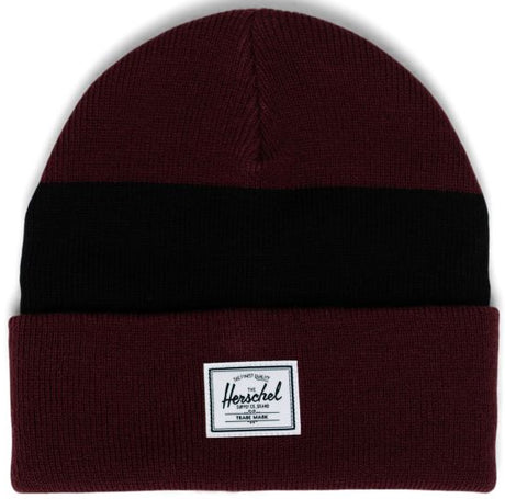 A maroon beanie with a black horizontal stripe and a white Herschel label on the front.