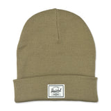 A khaki-colored knitted beanie hat with a folded cuff and a small rectangular brand label on the front.