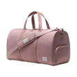A pink duffel bag with two top handles and a shoulder strap. It features a small front pocket and a brand label on the side.