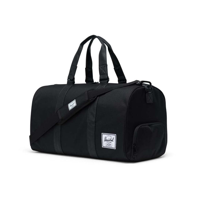 A black duffel bag with two top handles and a detachable shoulder strap. It features a small front pocket and a logo patch on the side.
